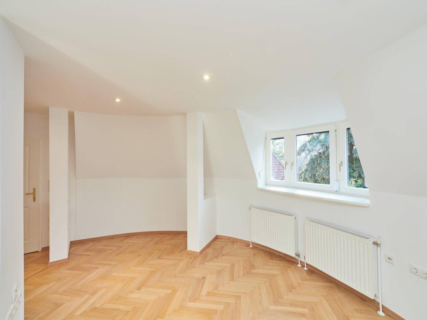 Geräumiges Zimmer mit Parkettboden, Dachschrägen und viel Tageslicht.