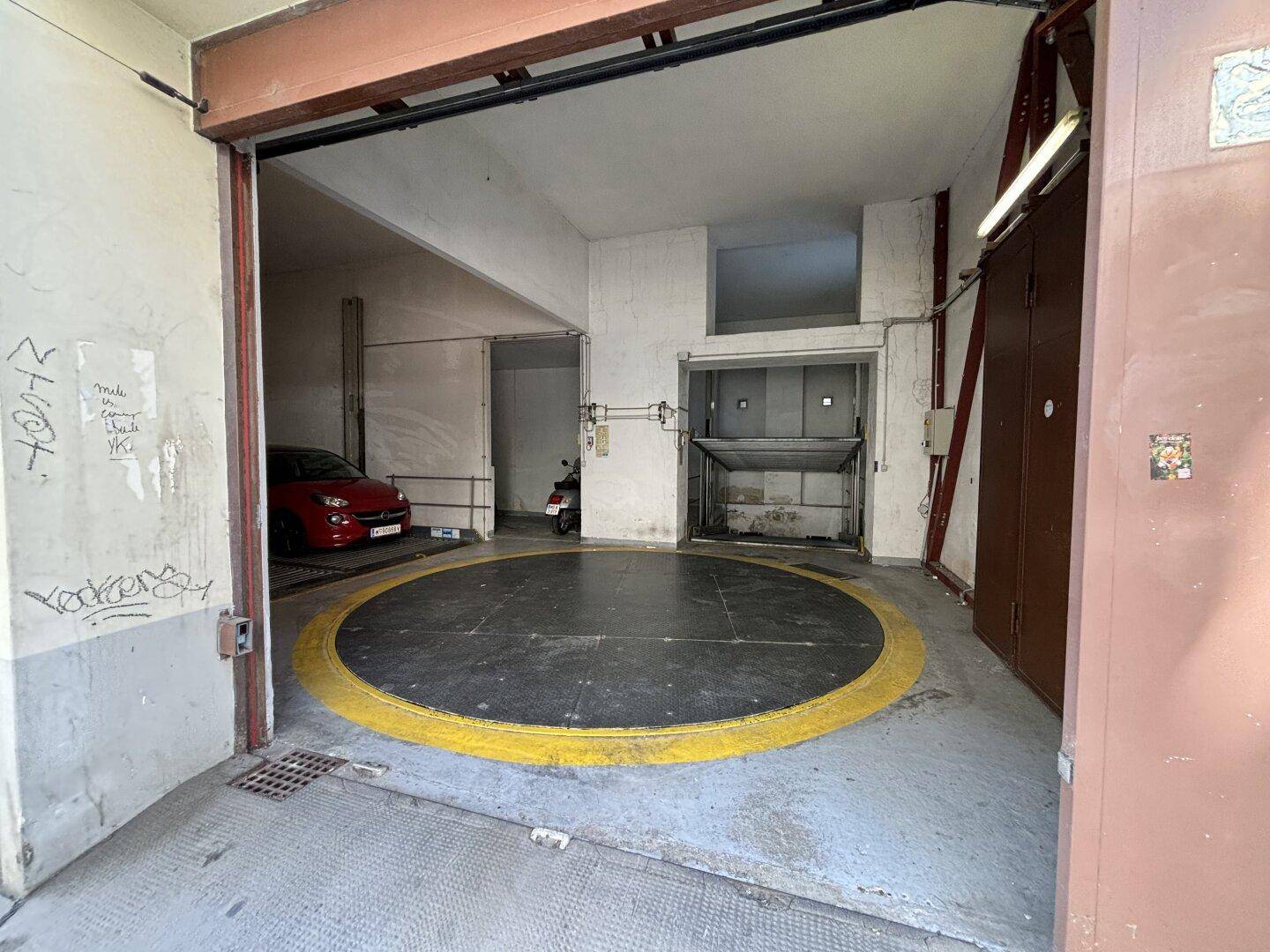 Eingangsbereich einer Tiefgarage mit einem Autodrehteller und einem automatischen Parksystem im Hintergrund.