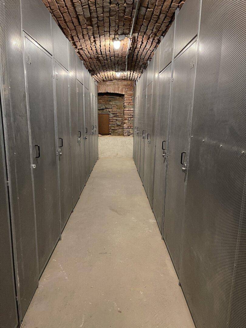 Kellerraum mit Reihen von Metallschränken und einer Ziegeldecke.