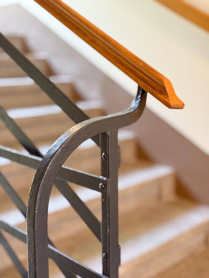 Detailansicht eines Treppengeländers mit elegantem Holzhandlauf und schmiedeeisernen Elementen.