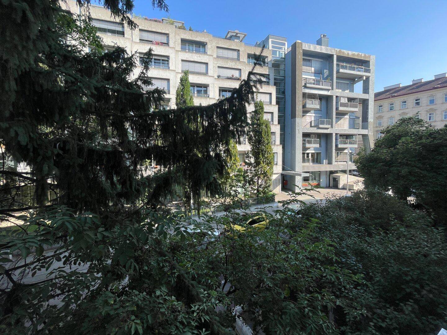 Moderne Wohngebäude mit vielen Fenstern und Balkonen, umgeben von üppigem Grün.