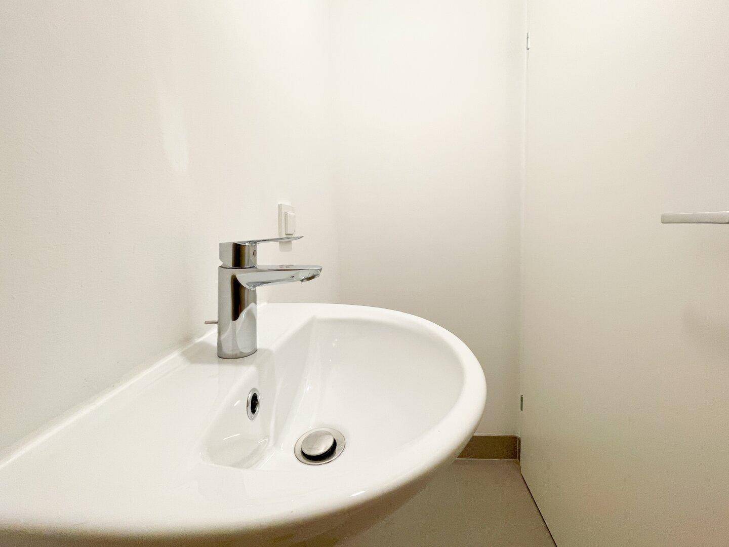 Modernes Einzelwaschbecken mit Chromarmatur in einem hellen, minimalistischen Raum.