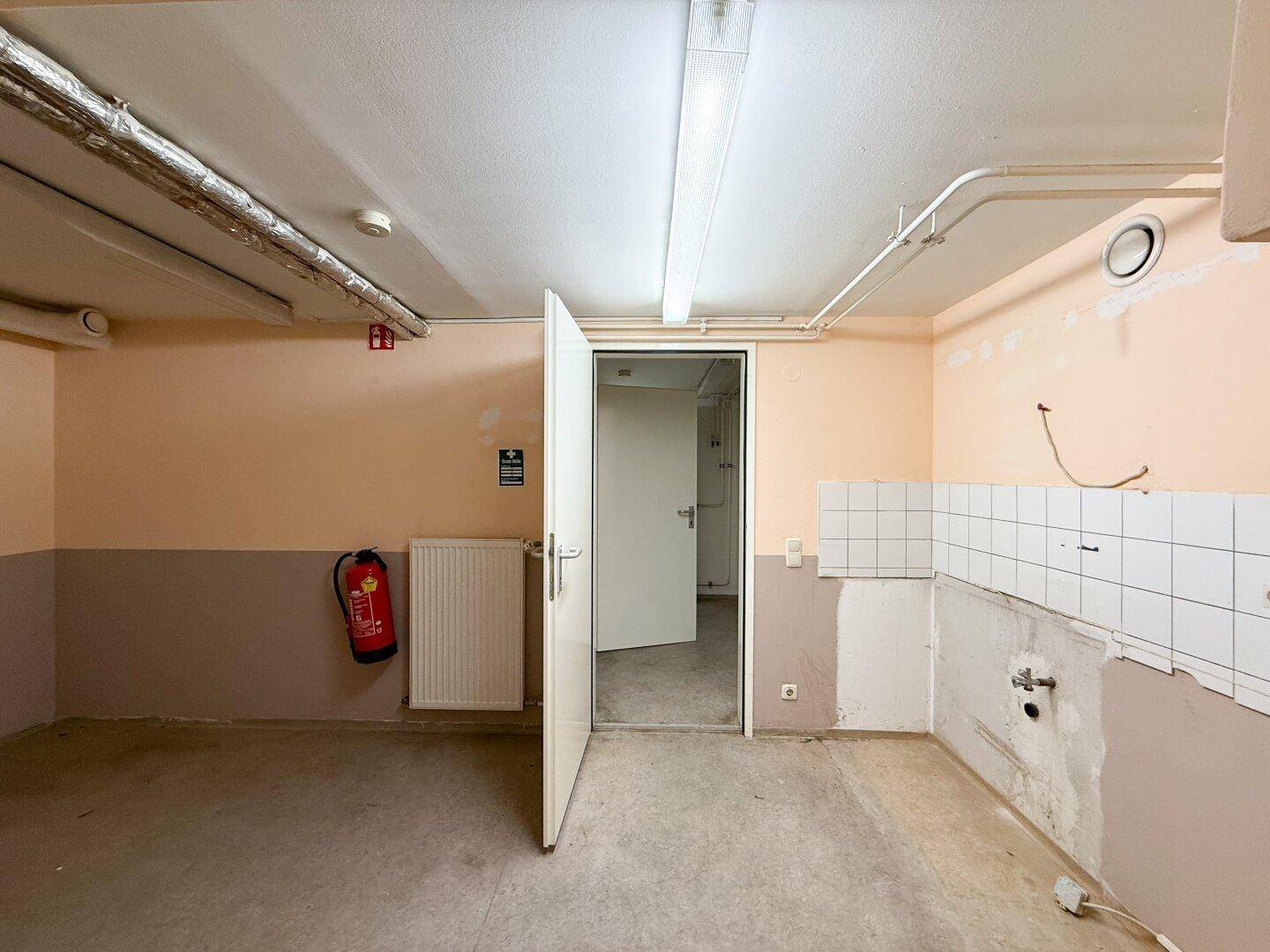 Kleiner Raum mit Heizkörper, teilweise gefliesten Wänden und deutlichem Renovierungsbedarf.