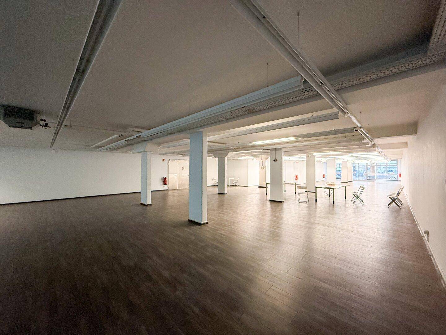 Geräumiger Gewerberaum mit Tischen und Stühlen, bereit für eine Veranstaltung oder Nutzung.