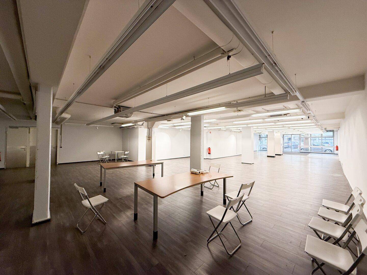 Heller Gewerberaum mit Tischen und Stühlen, ideal für Büros oder Veranstaltungen.