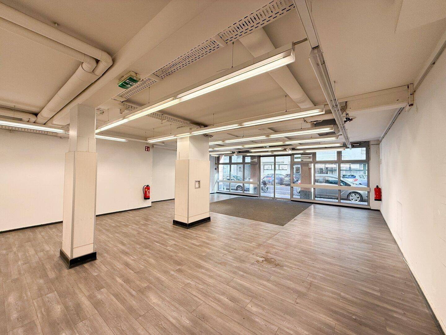 Eingangsbereich des Gewerberaums mit breiter Glasfront und hellem Laminatboden.