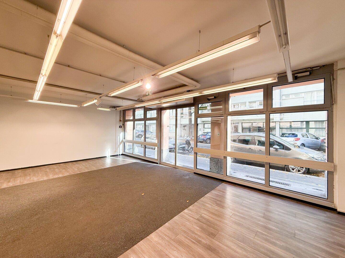 Eingangsbereich mit großen Glasfenstern und Blick auf die belebte Straße.