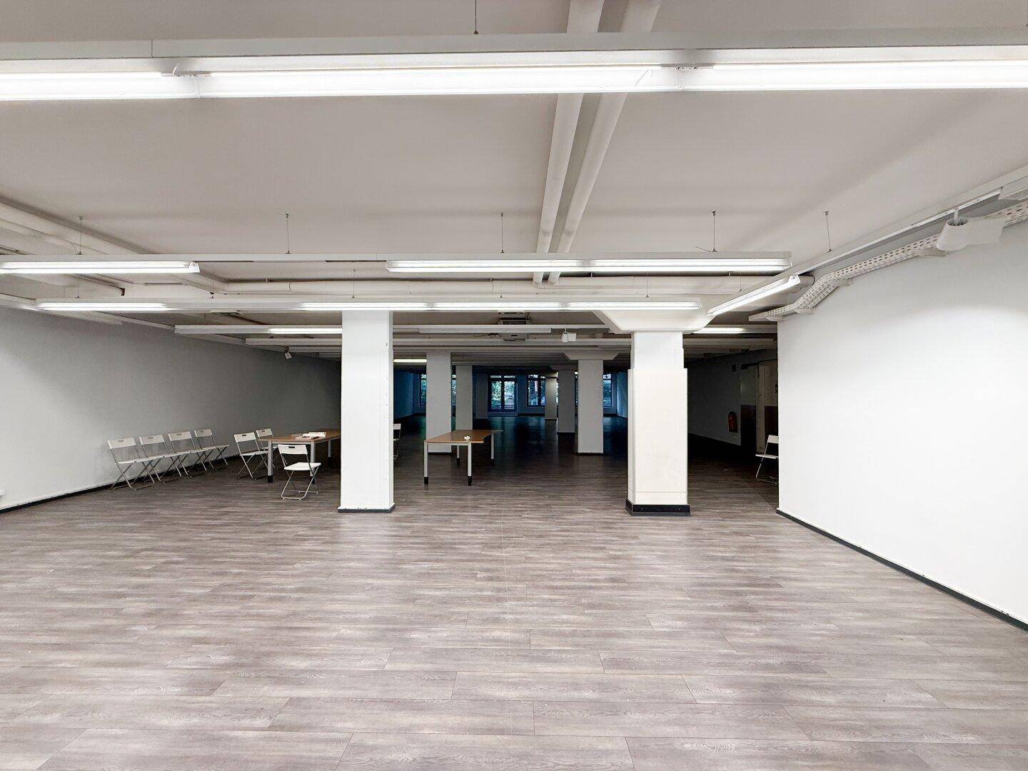 Eine ruhige Stadtstraße mit parkenden Autos und hohen Gebäuden unter blauem Himmel.