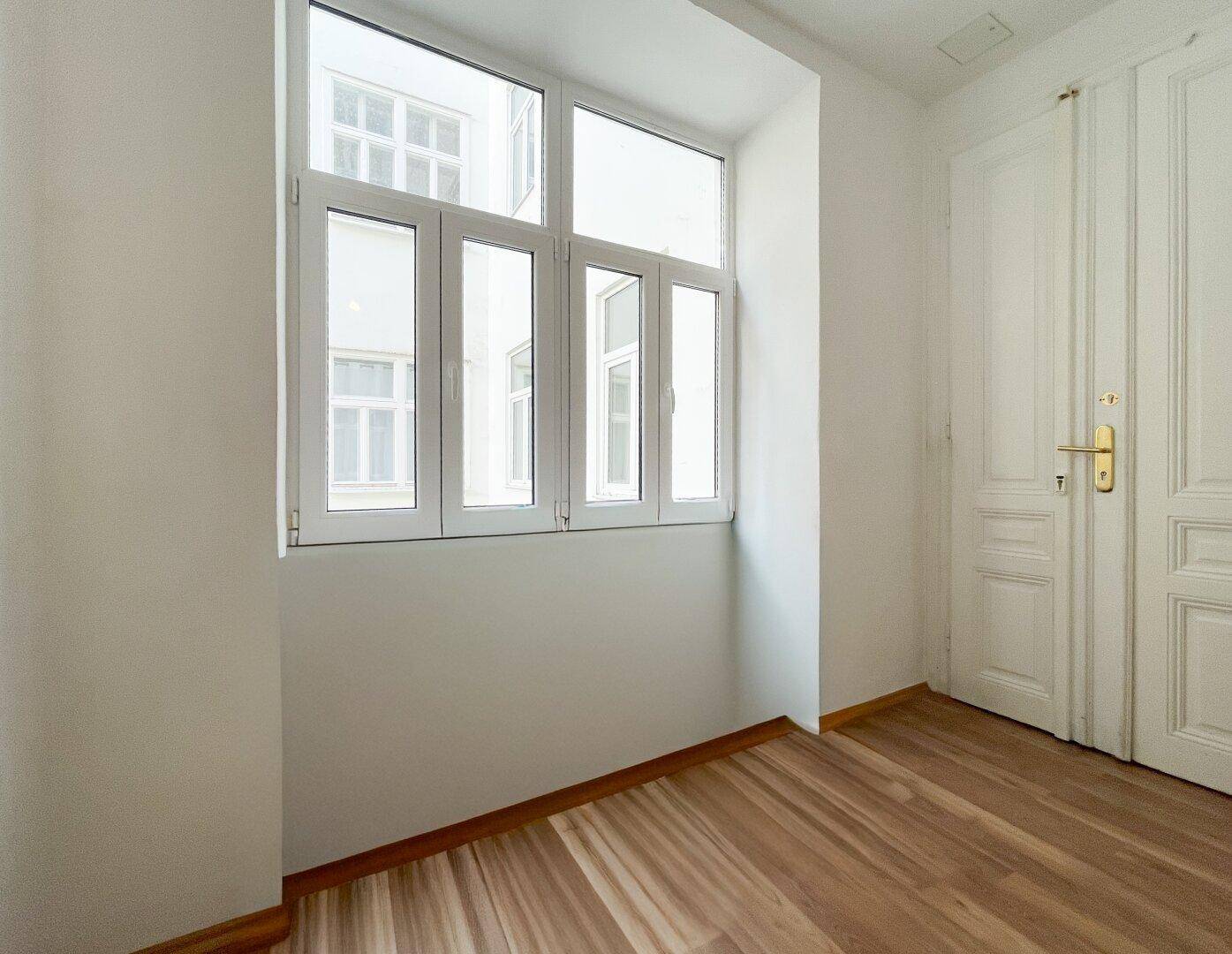 Kleiner Raum mit großem Fenster und klassischer Flügeltür, bietet viel Tageslicht.
