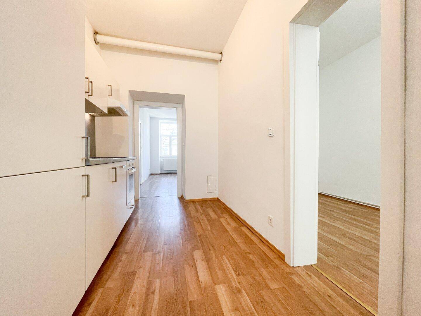 Heller Flur mit Laminatboden, der zu einer modernen Küche und weiteren Räumen führt.