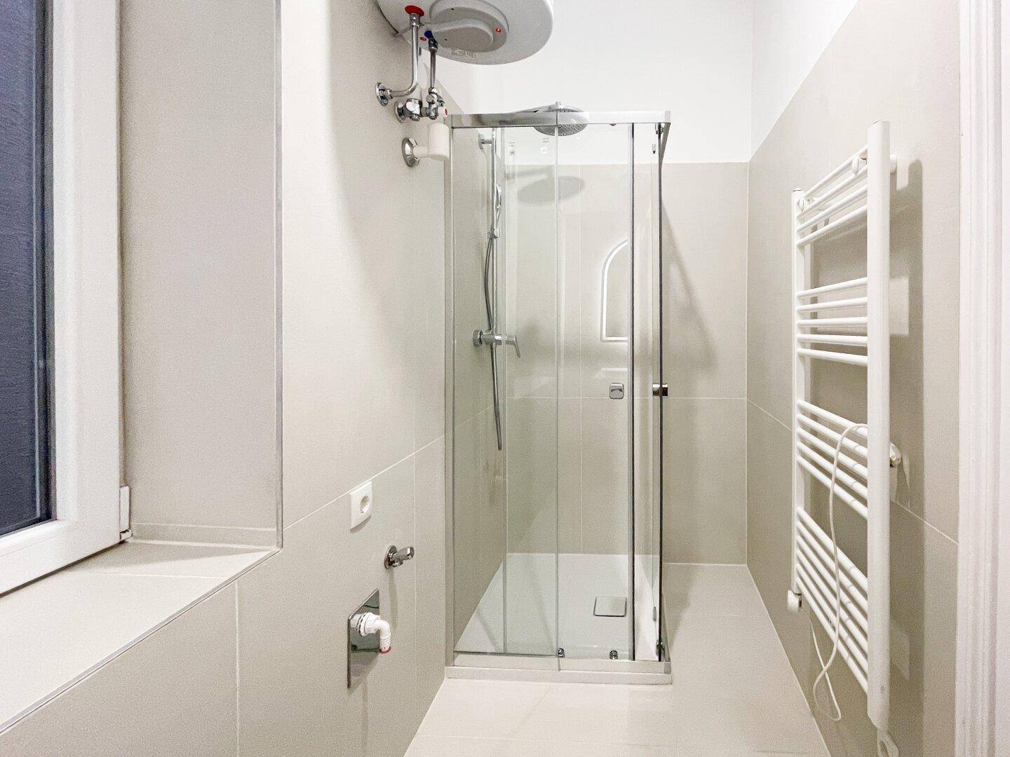 Modernes Badezimmer mit einer Glasduschkabine und einem praktischen beheizten Handtuchhalter.