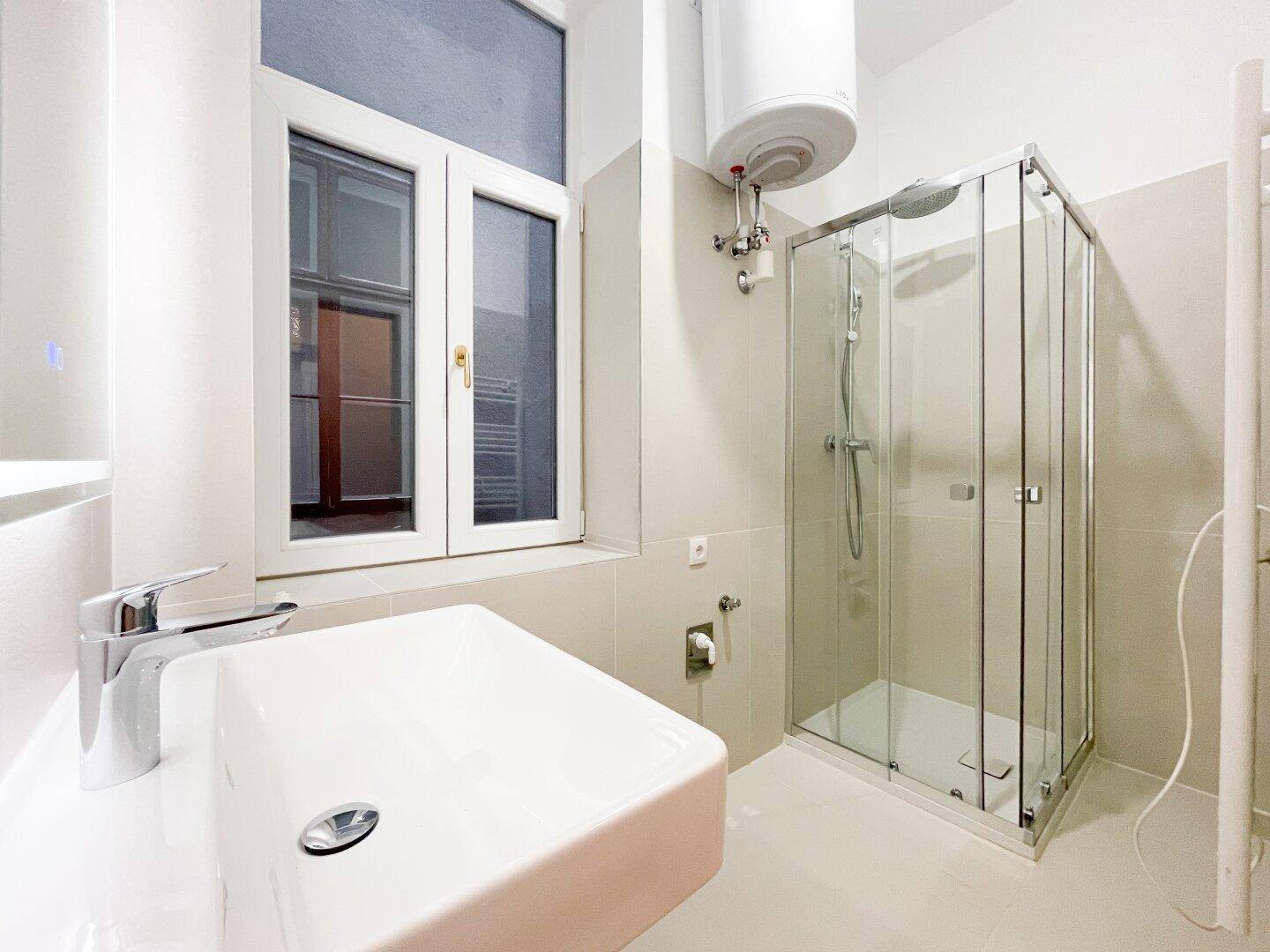 Modernes Badezimmer mit Waschbecken, Duschkabine, beheiztem Handtuchhalter und einem Fenster.