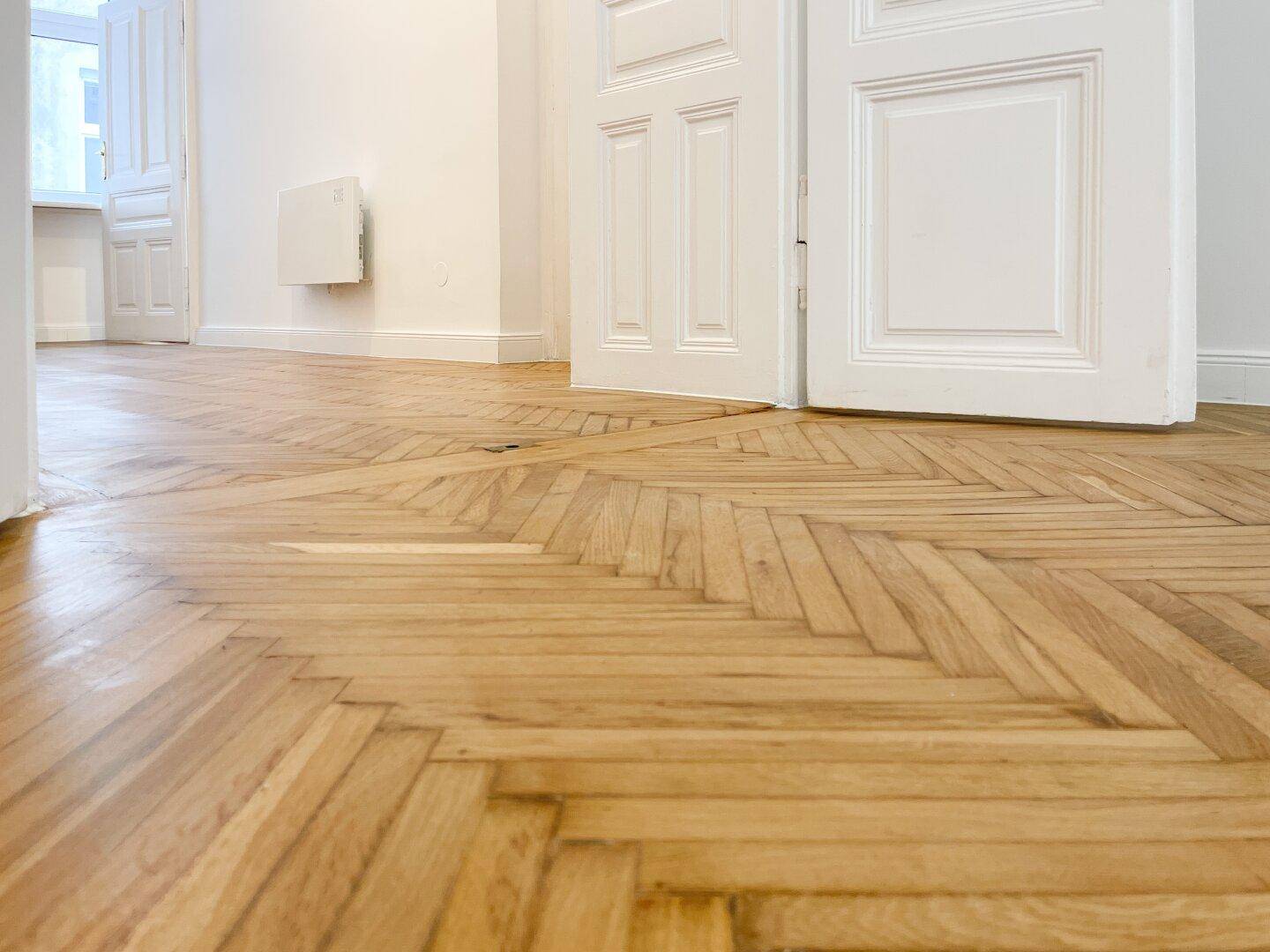 Nahaufnahme des frisch verlegten Fischgrätparketts aus hellem Holz, das den Boden schmückt.