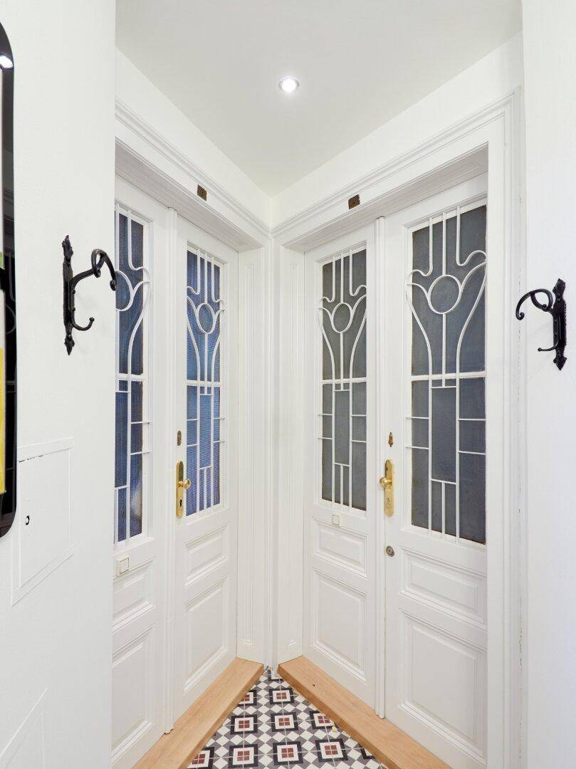 Detailansicht von zwei eleganten Eingangstüren mit kunstvollen Glasausschnitten und Haken.