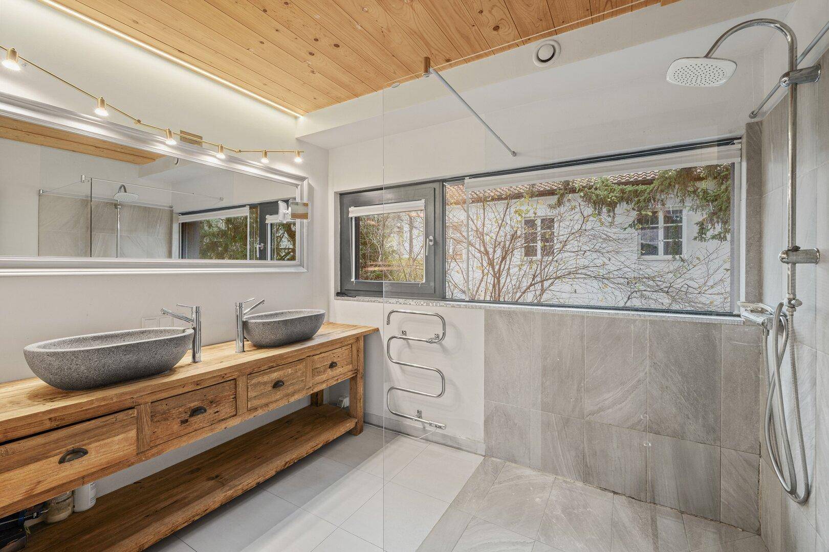 Modernes Badezimmer mit Doppelwaschbecken, großer Dusche und Holzbalkendecke.
