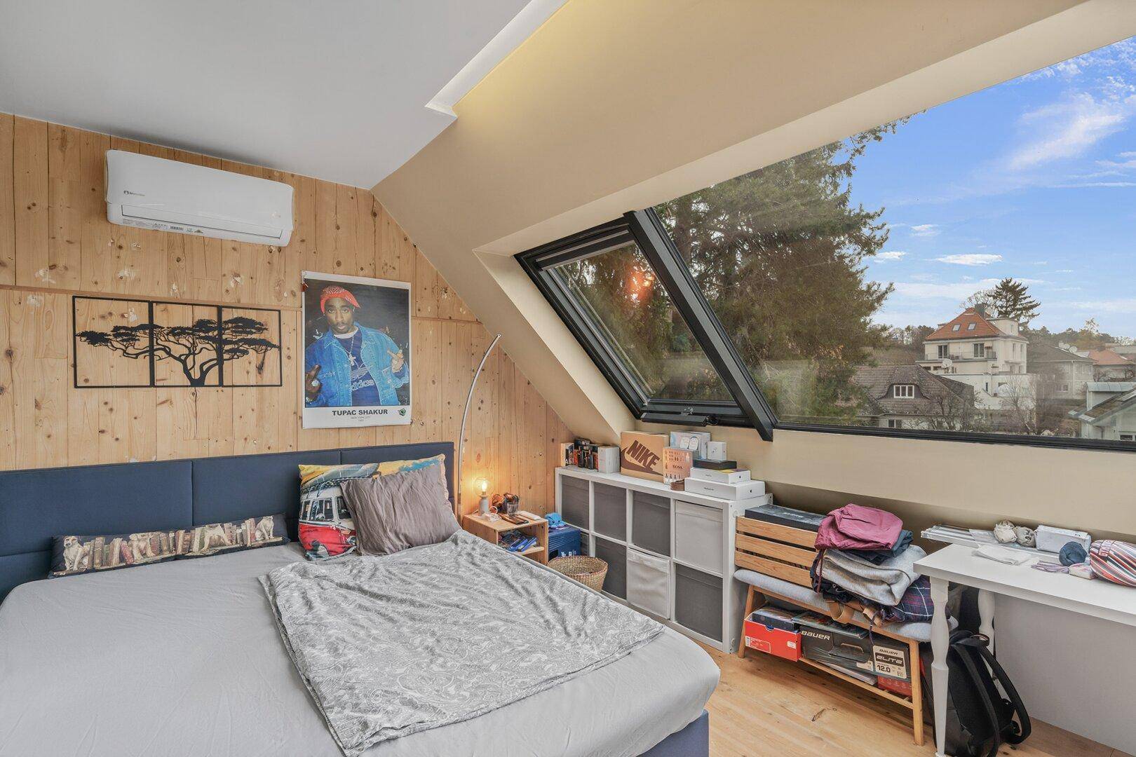 Gemütliches Schlafzimmer mit Dachschräge, Holzvertäfelung und großem Dachfenster.
