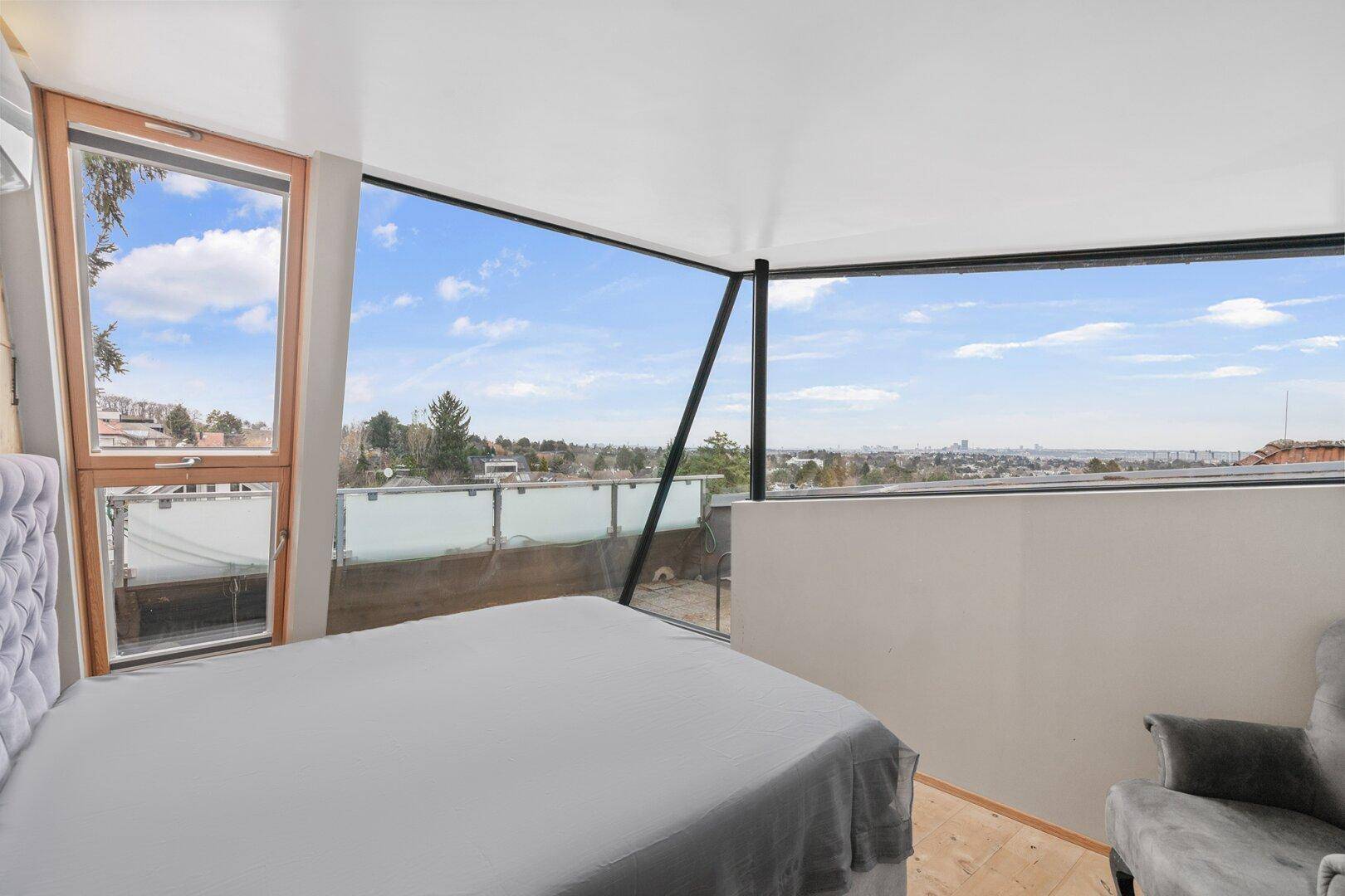 Schlafzimmer mit beeindruckendem Panoramablick durch große Fenster.