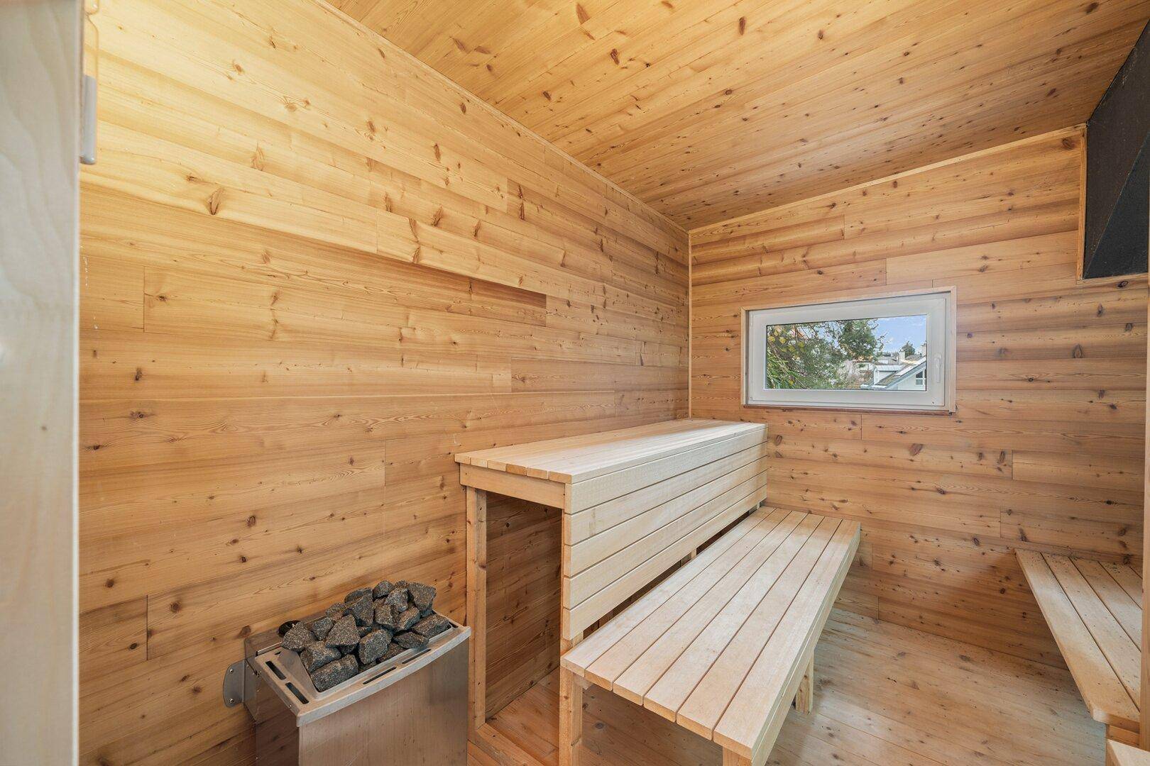 Traditionelle Holzsauna mit Bänken und Saunaofen für entspannende Momente.
