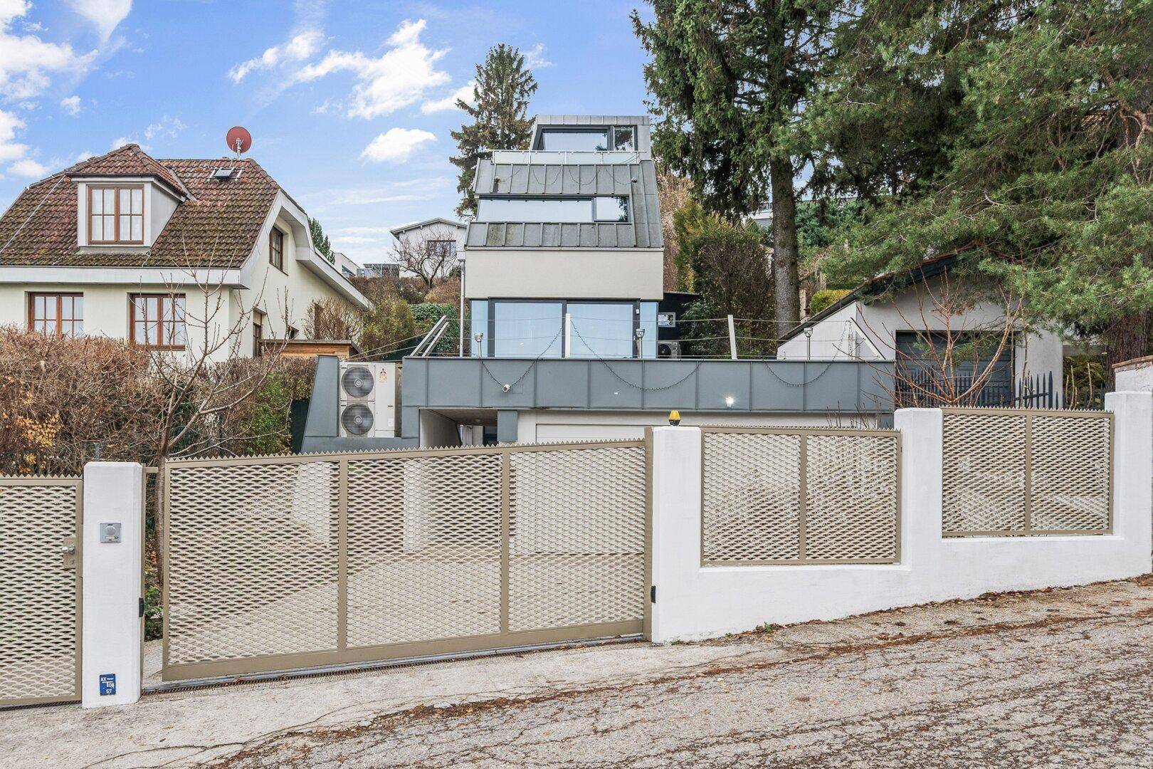 Eingangsbereich des modernen Hauses mit Tor und gepflegter Außenanlage.