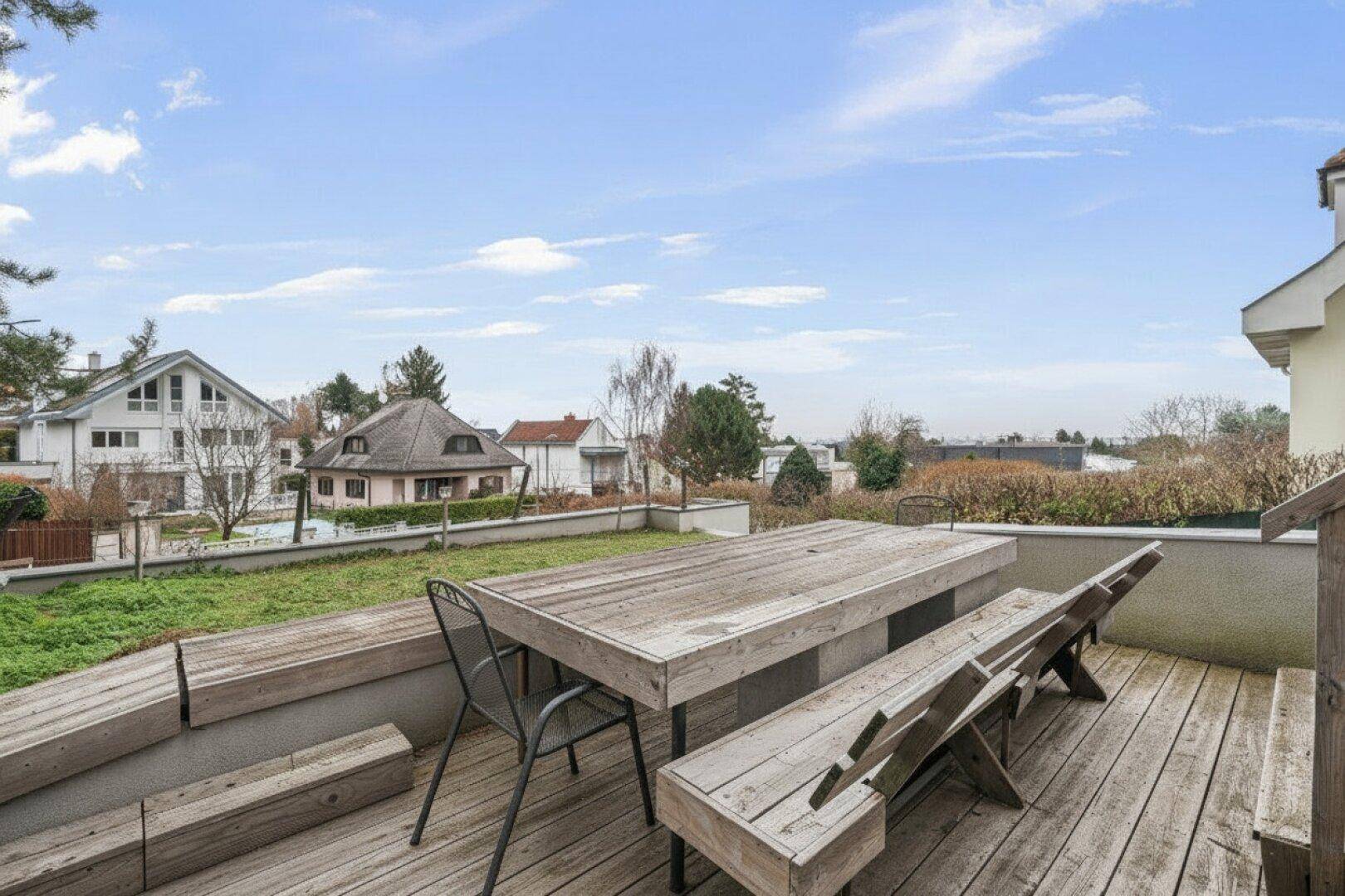 Große Holzterrasse mit rustikalen Sitzgelegenheiten und Blick auf die Nachbarschaft.