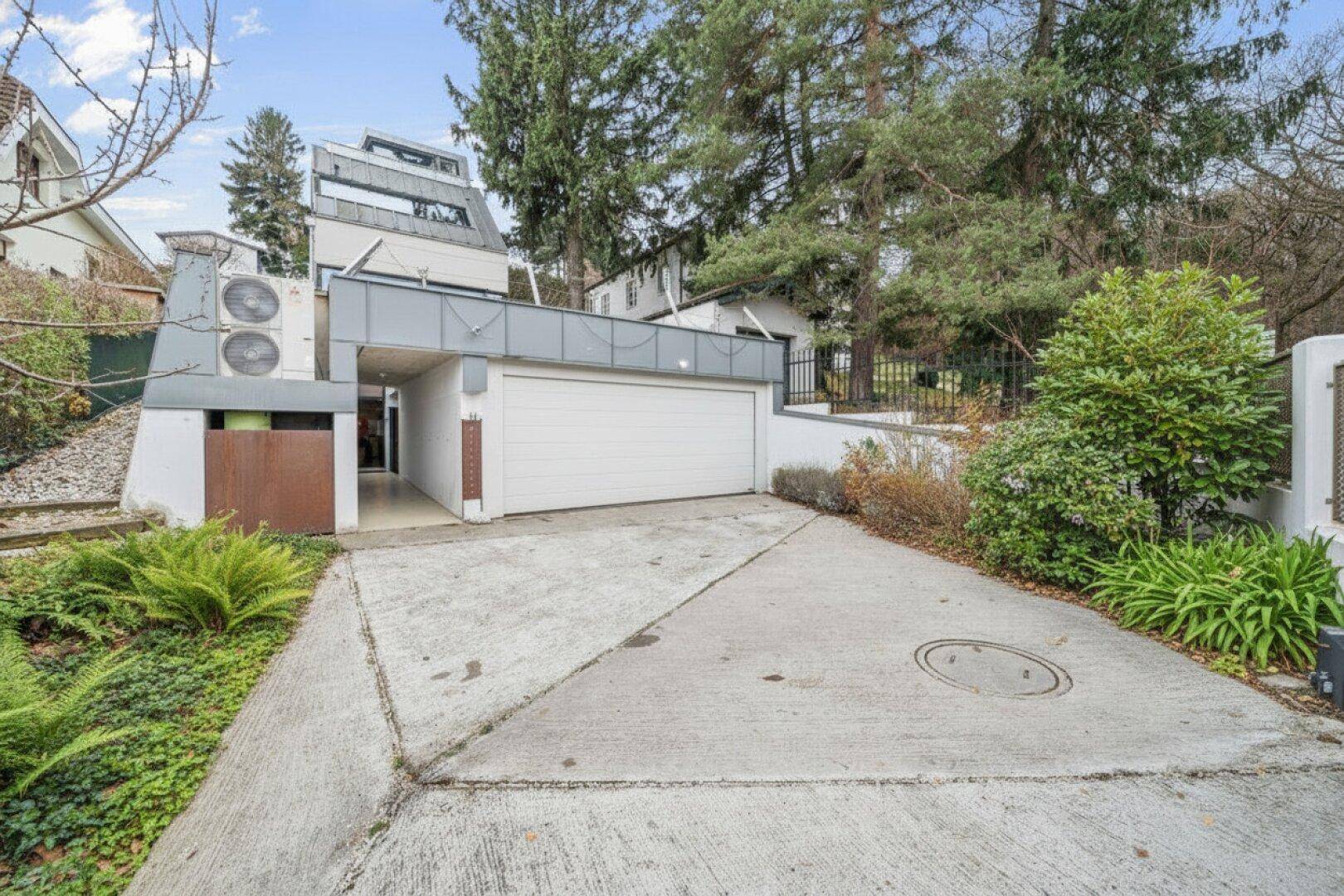 Garageneinfahrt mit Betonfläche und modernem Garagentor.