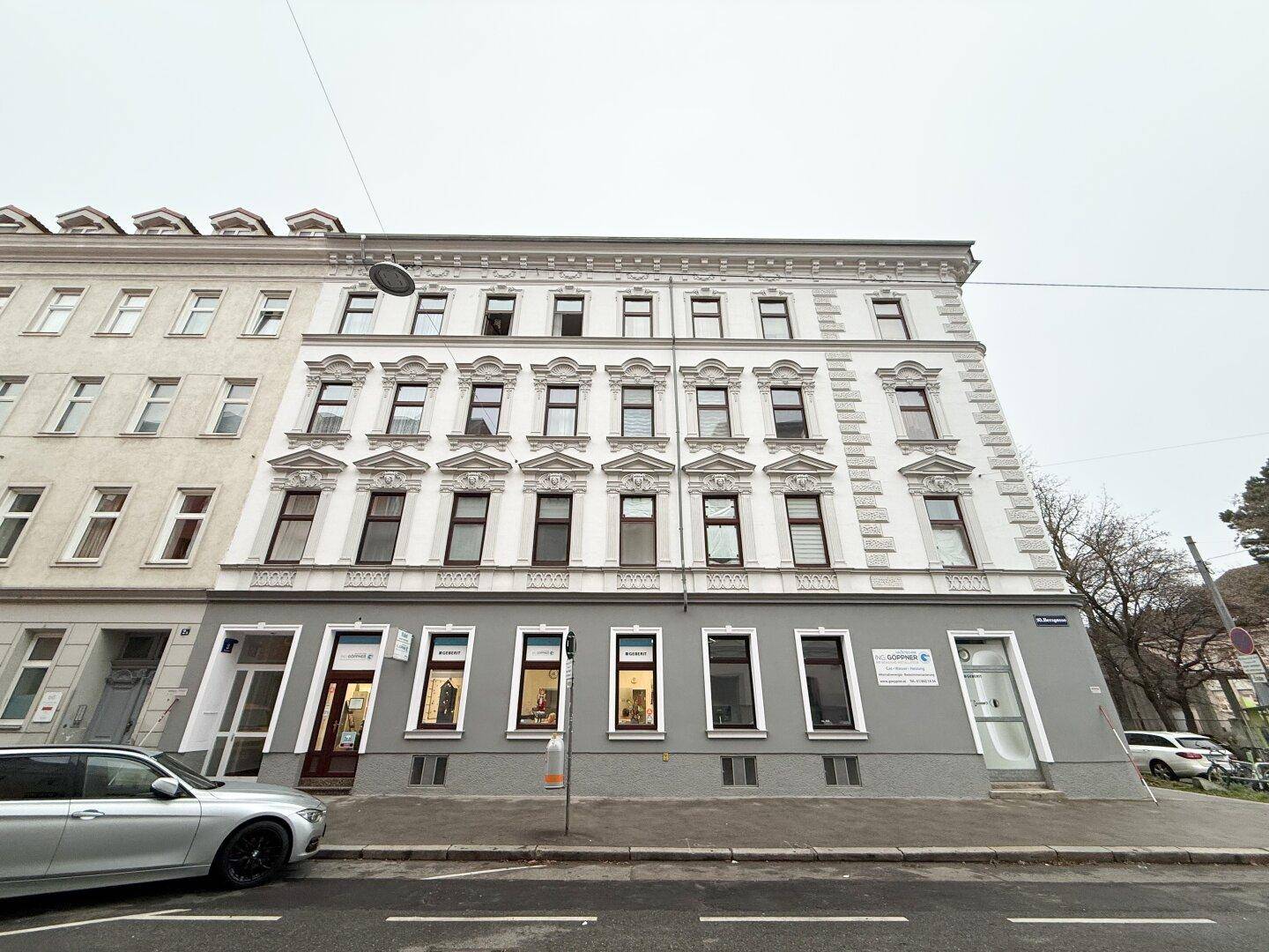 Historische Gebäudefassade mit vielen Fenstern und Geschäften im Erdgeschoss.