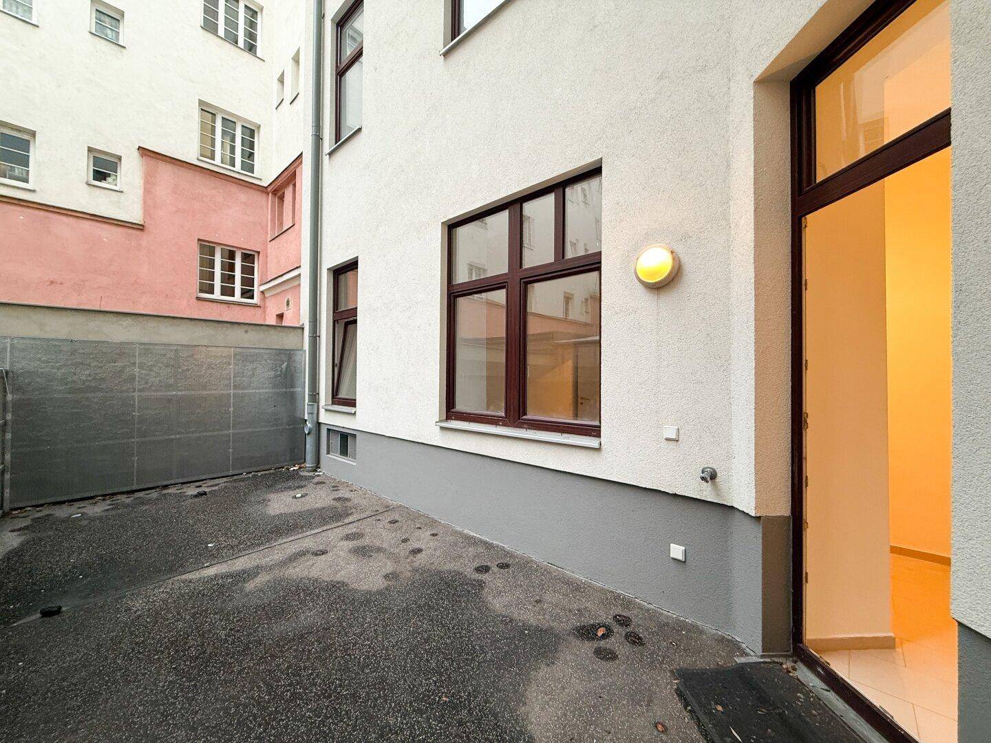 Kleiner gepflasterter Innenhofbereich mit Zugang zur Wohnung und Blick auf die Gebäudefassade.