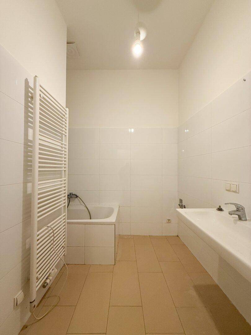 Badezimmer mit Badewanne, breitem Waschbecken und einem Handtuchheizkörper.