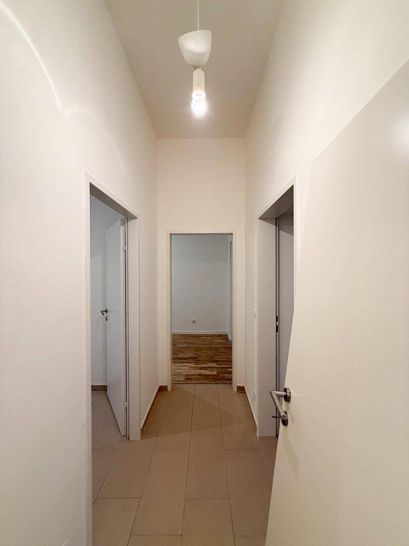 Heller Flur mit Fliesenboden und Türen zu verschiedenen Zimmern der Wohnung.