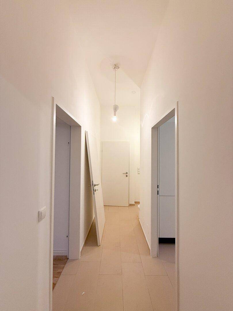 Heller Flur mit Fliesenboden und mehreren Türen, die zu den Zimmern führen.