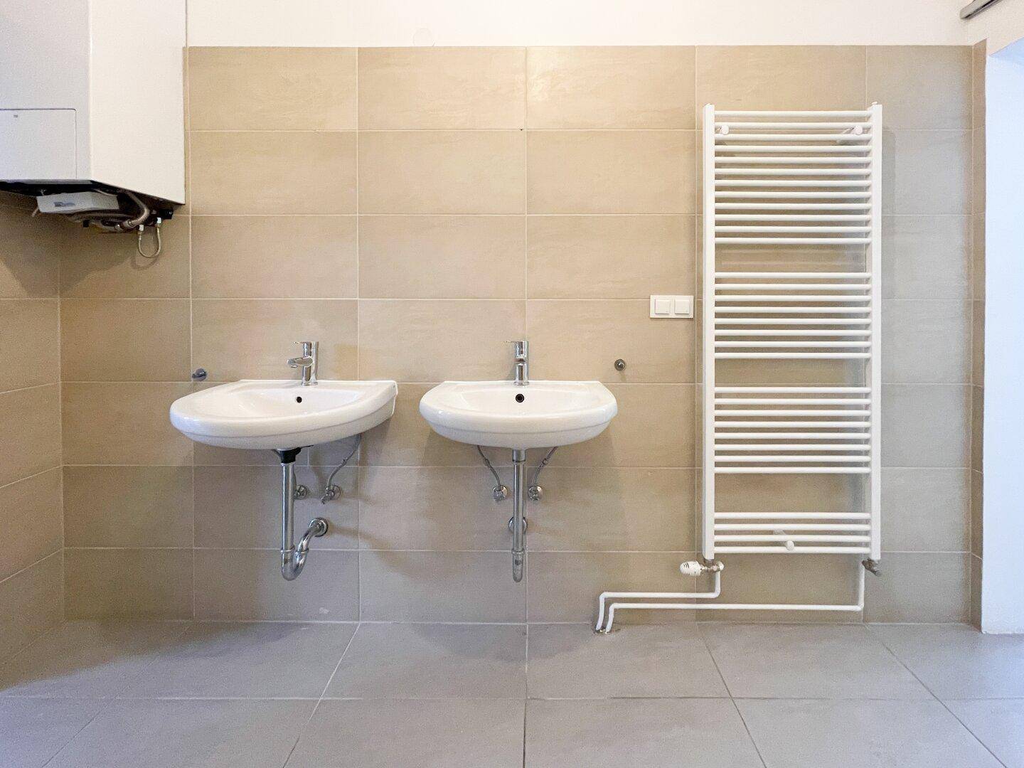 Detailansicht des Badezimmers mit zwei Waschbecken und einem modernen Handtuchheizkörper.