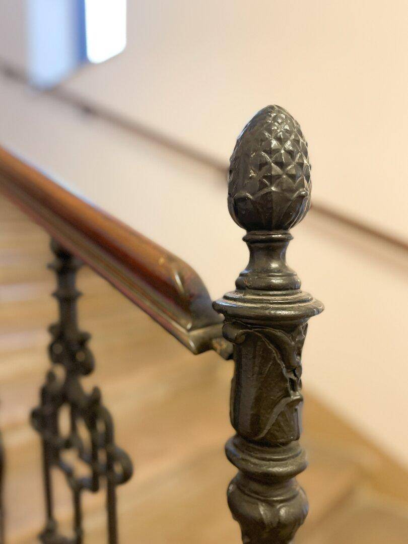 Detail des schmiedeeisernen Treppengeländers mit dekorativer Zierspitze, die die Handwerkskunst zeigt.
