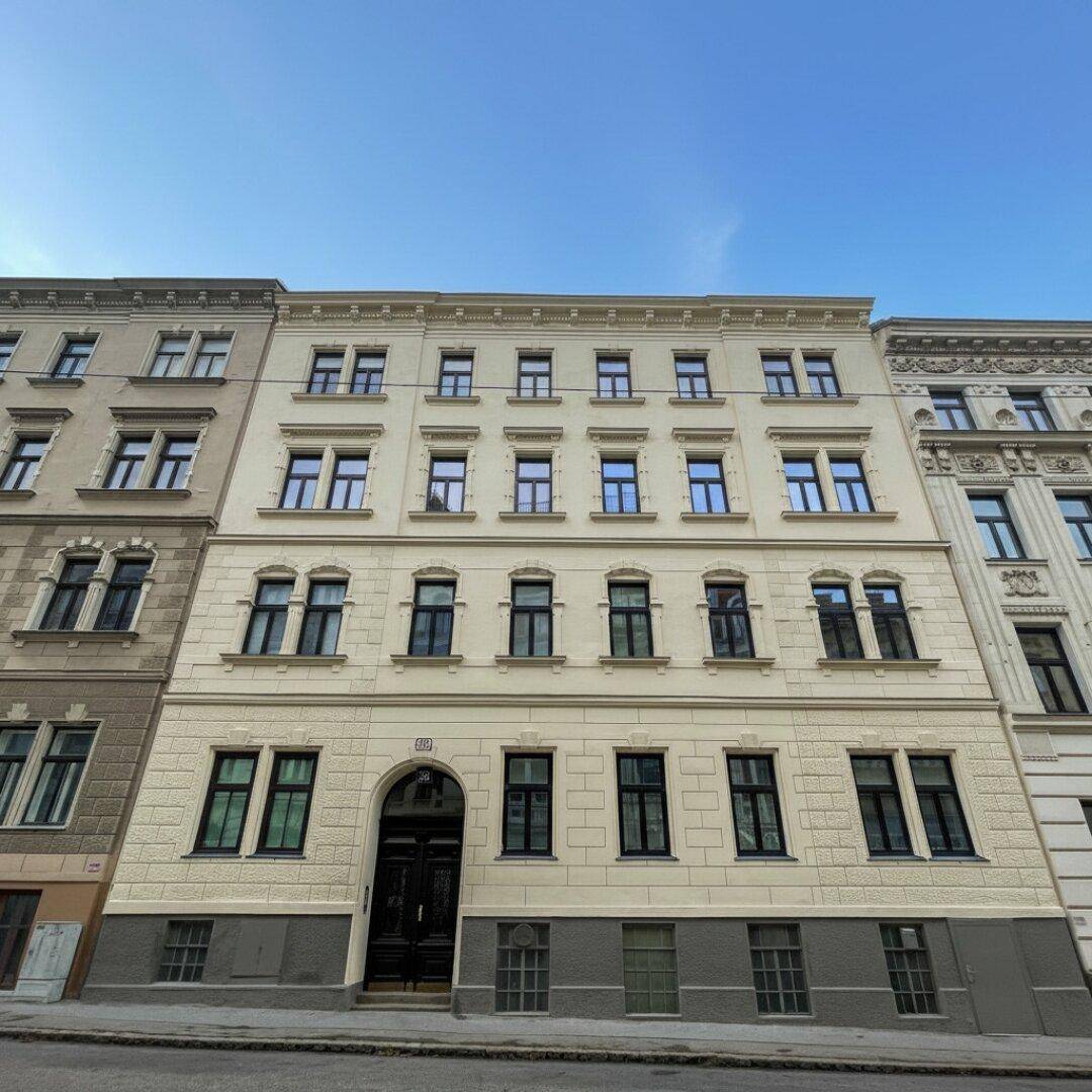 Die historische Fassade des Gebäudes mit vielen Fenstern und klassischer Architektur unter blauem Himmel.