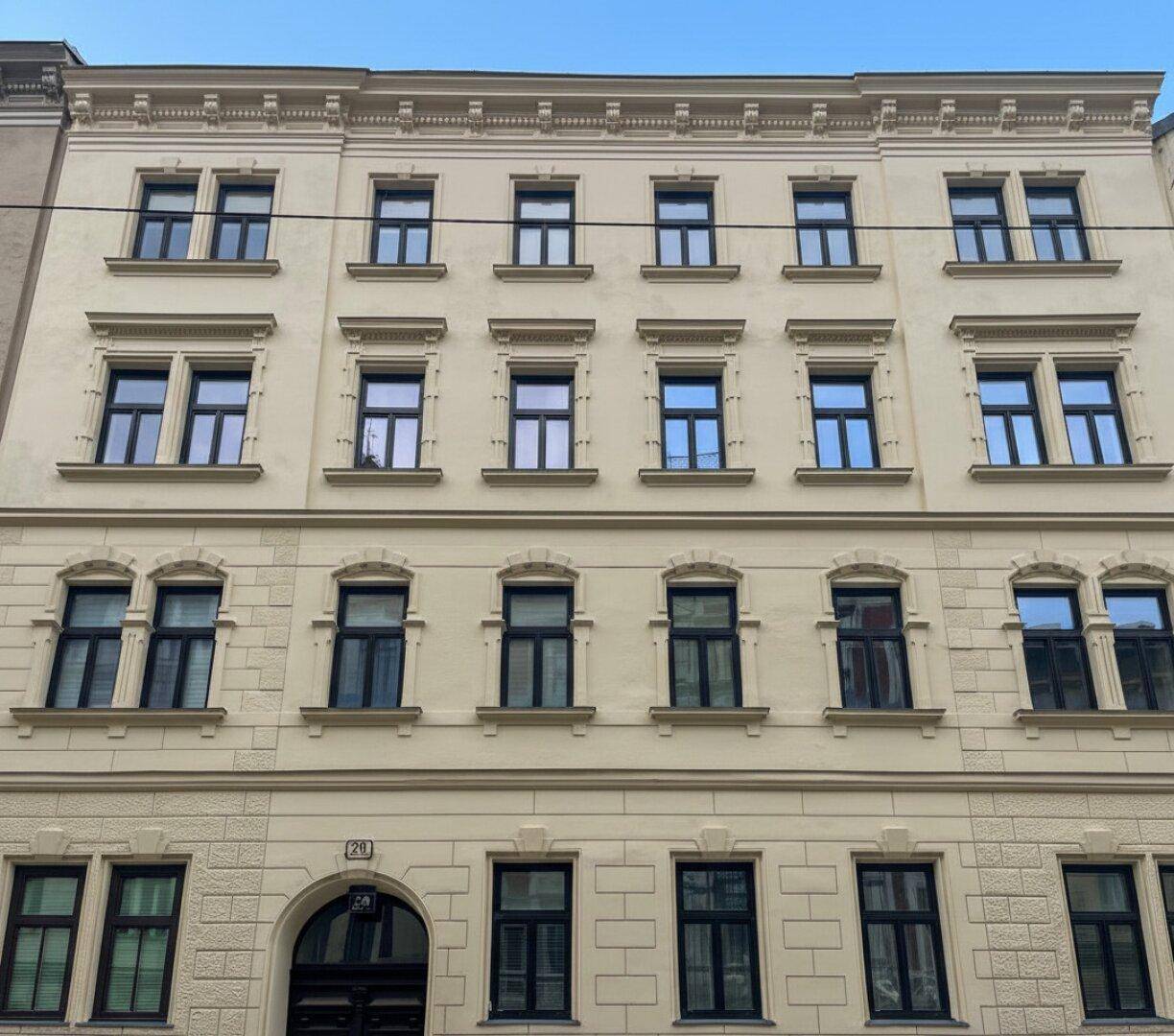 Die historische Fassade des Gebäudes mit vielen Fenstern und klassischer Architektur unter blauem Himmel.