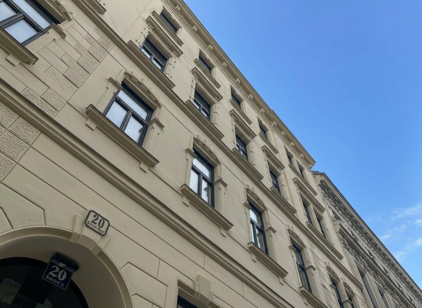 Schräge Ansicht der historischen Fassade mit dekorativen Elementen und blauer Himmel im Hintergrund.