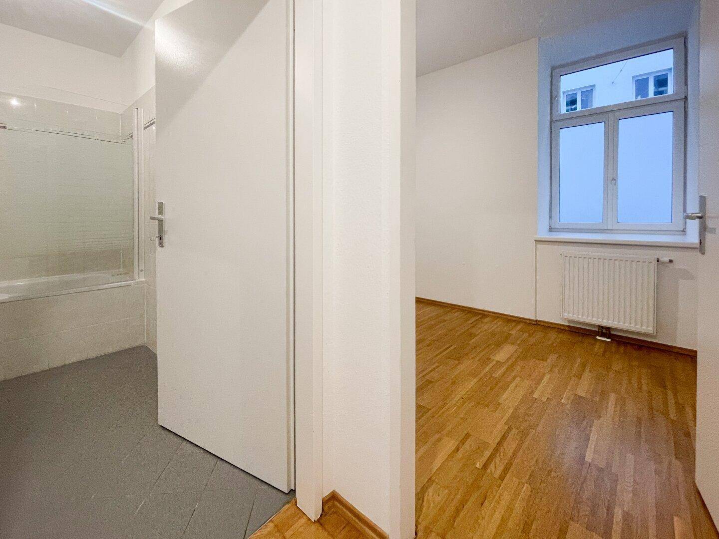 Flur mit Parkettboden und Zugang zu einem Zimmer sowie einem Badezimmer.