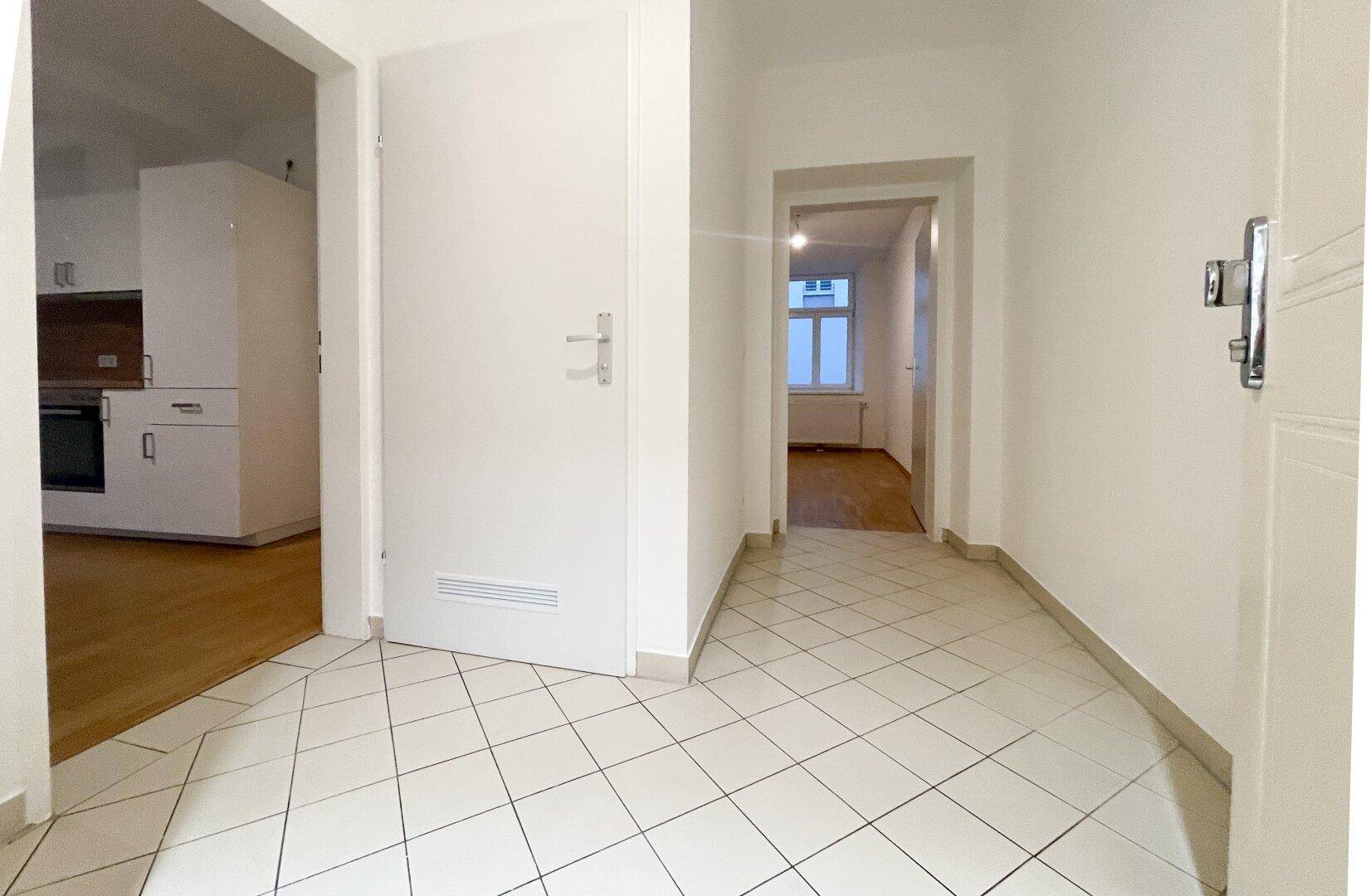 Eingangsbereich mit hellen Fliesen und Zugang zu verschiedenen Räumen der Wohnung.