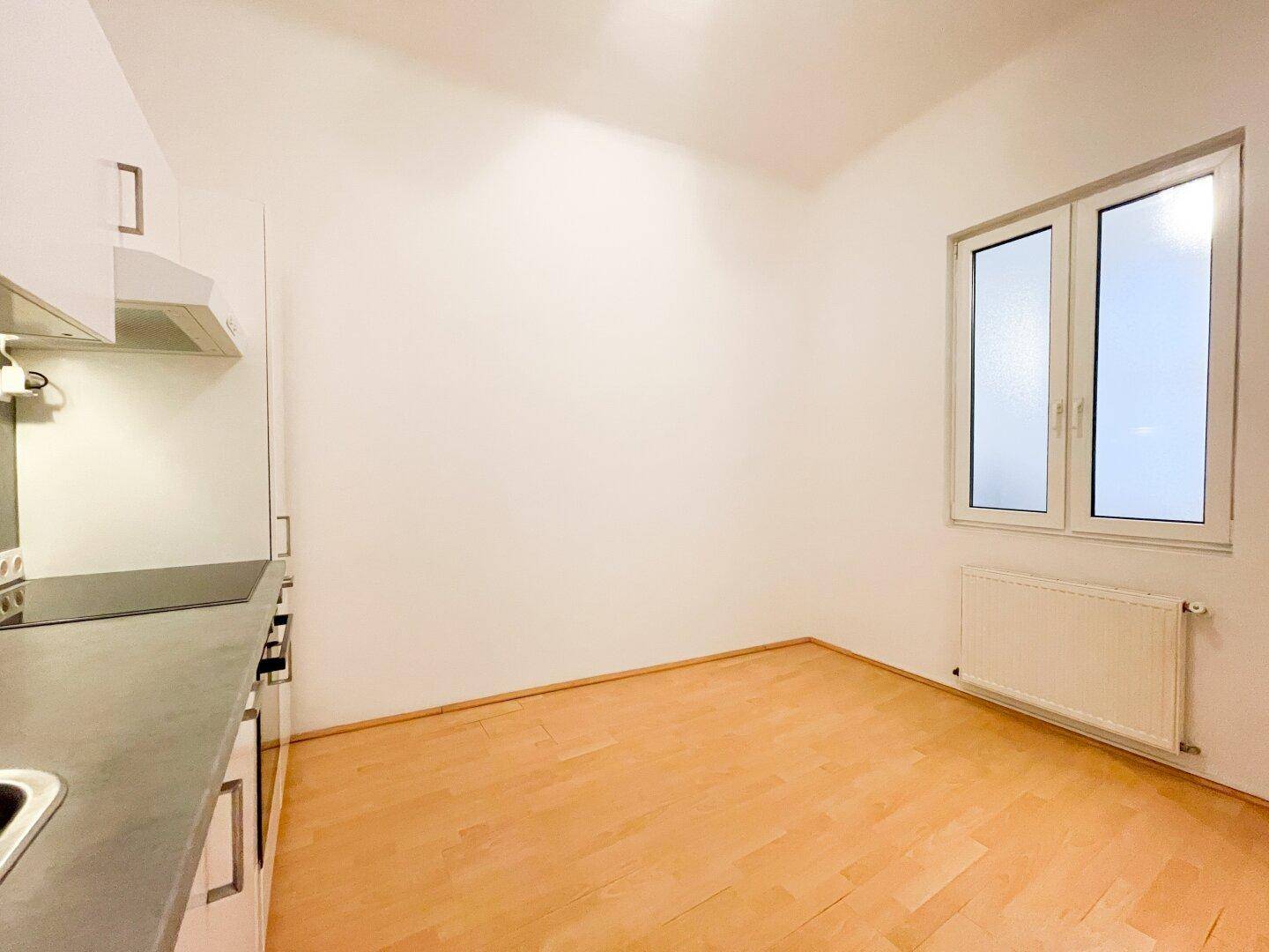 Detailansicht der Küche mit Arbeitsplatte, Kochfeld und großem Fenster.