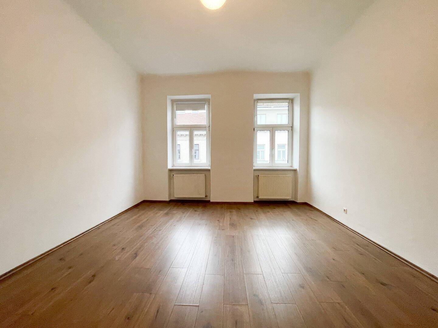 Heller Raum mit schönem Holzboden und zwei Fenstern, bietet viel Tageslicht.