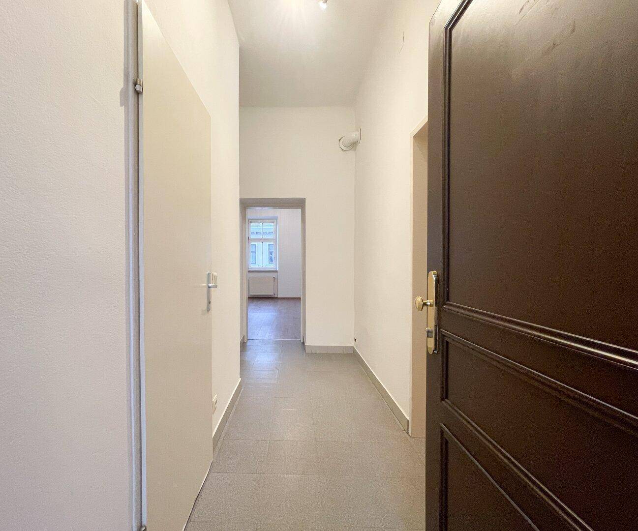 Heller Flur mit Fliesenboden und Zugang zu verschiedenen Räumen der Wohnung.