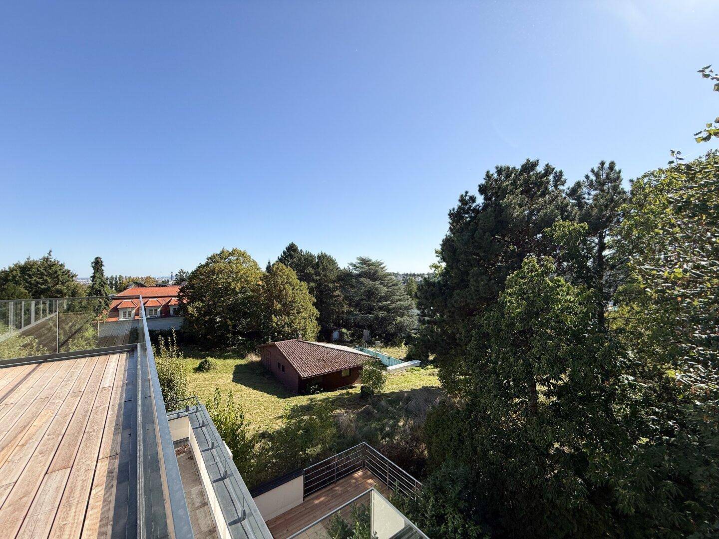 Panoramablick von der Terrasse auf einen weitläufigen Garten und die umliegende Landschaft.