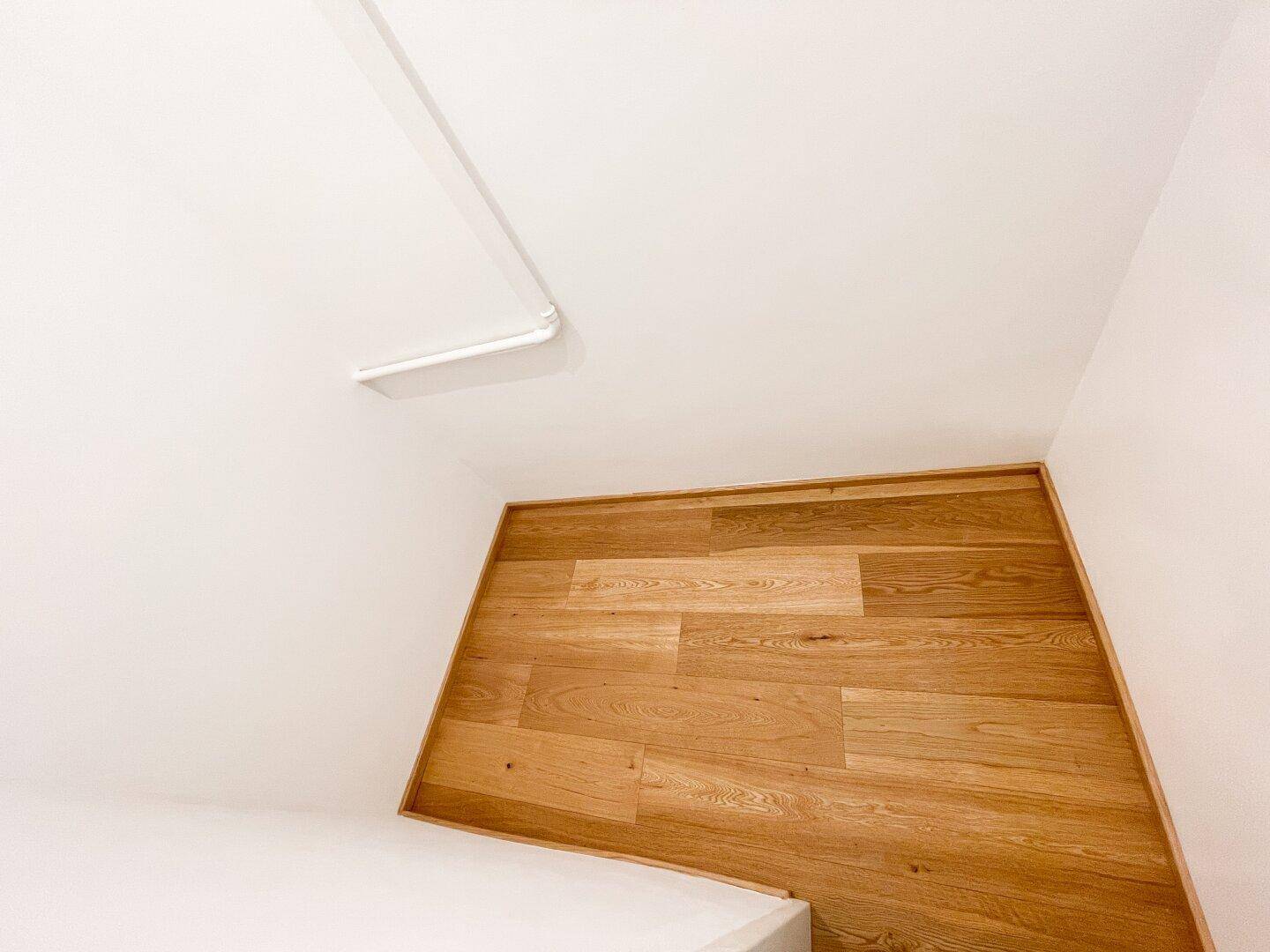 Detailaufnahme des Deckenbereichs und des hellen Holzparkettbodens in einem modernen Raum.