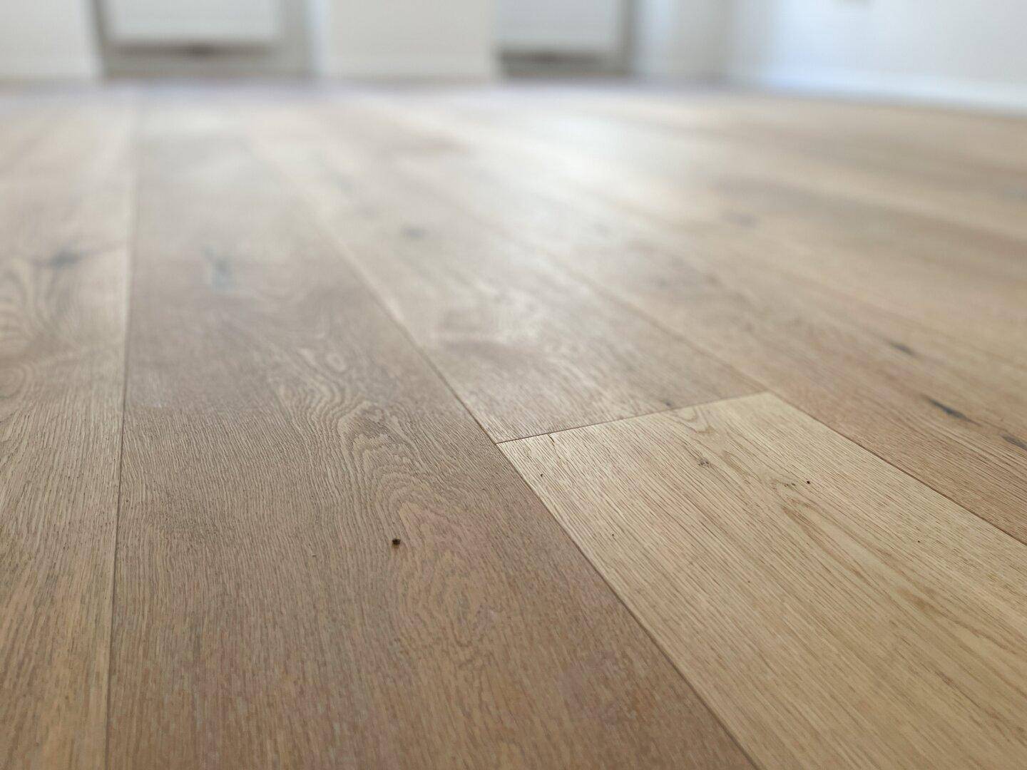 Detailansicht des neuen, hellen Holzparkettbodens in einem Wohnraum, der frisch verlegt wurde.