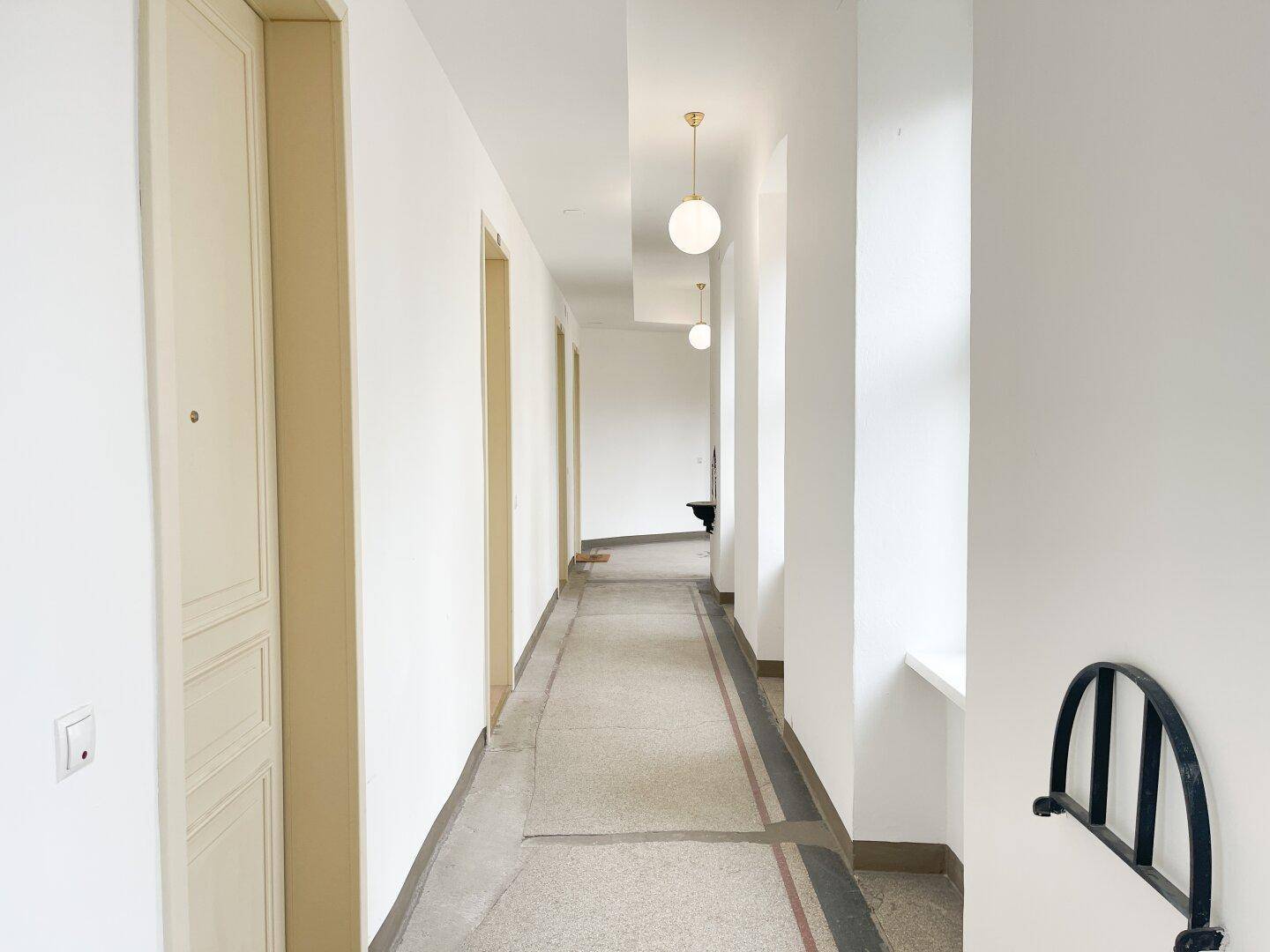 Heller Flur mit mehreren Türen und einem historischen Wandhalter in einem Altbau mit hohen Decken.