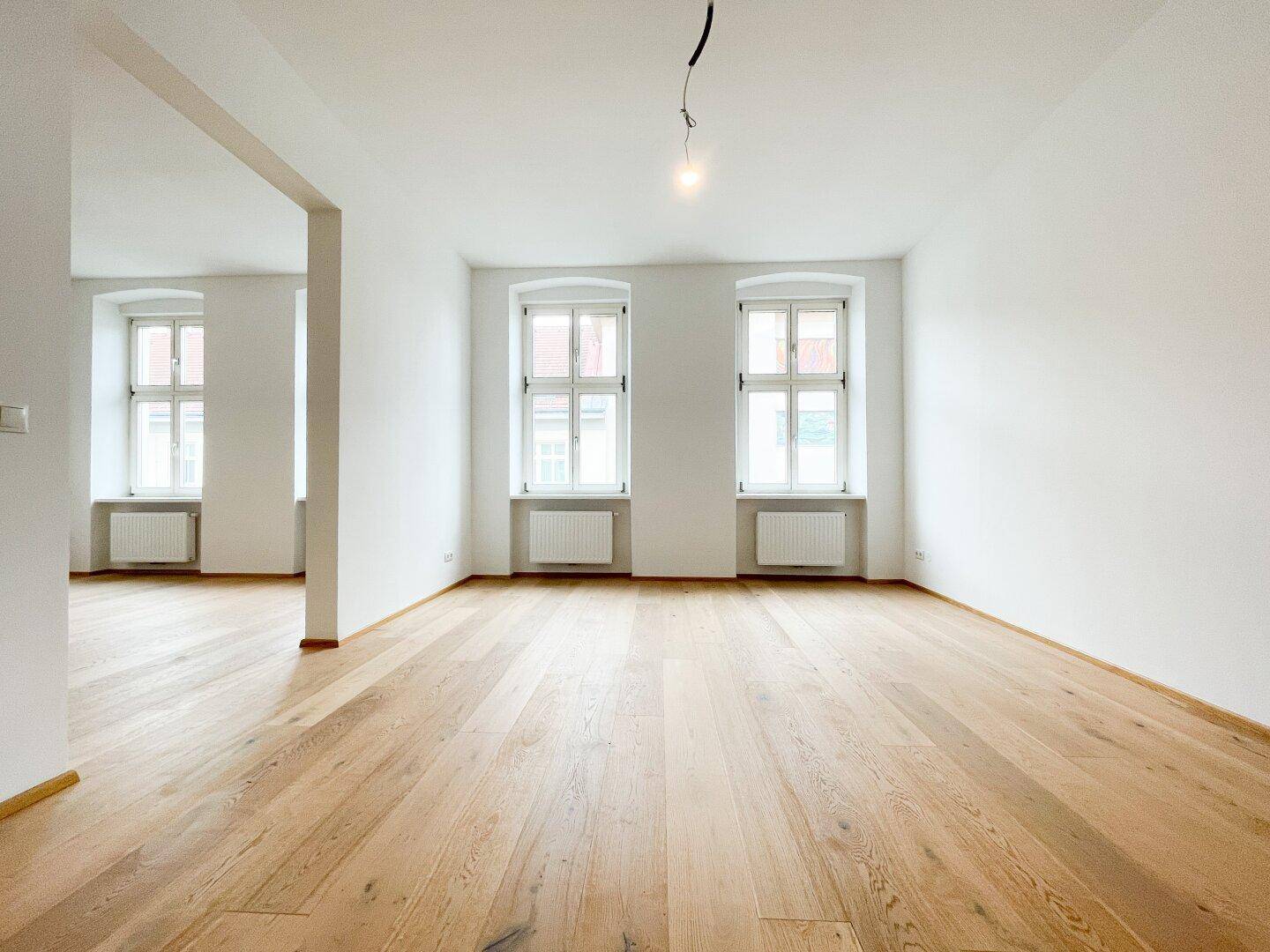 Helles, geräumiges Zimmer mit Parkettboden und zwei Fenstern, bereit zur Einrichtung.