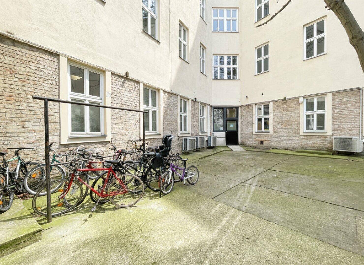 Innenhof mit Fahrradabstellplätzen und Gebäudefassaden mit vielen Fenstern.