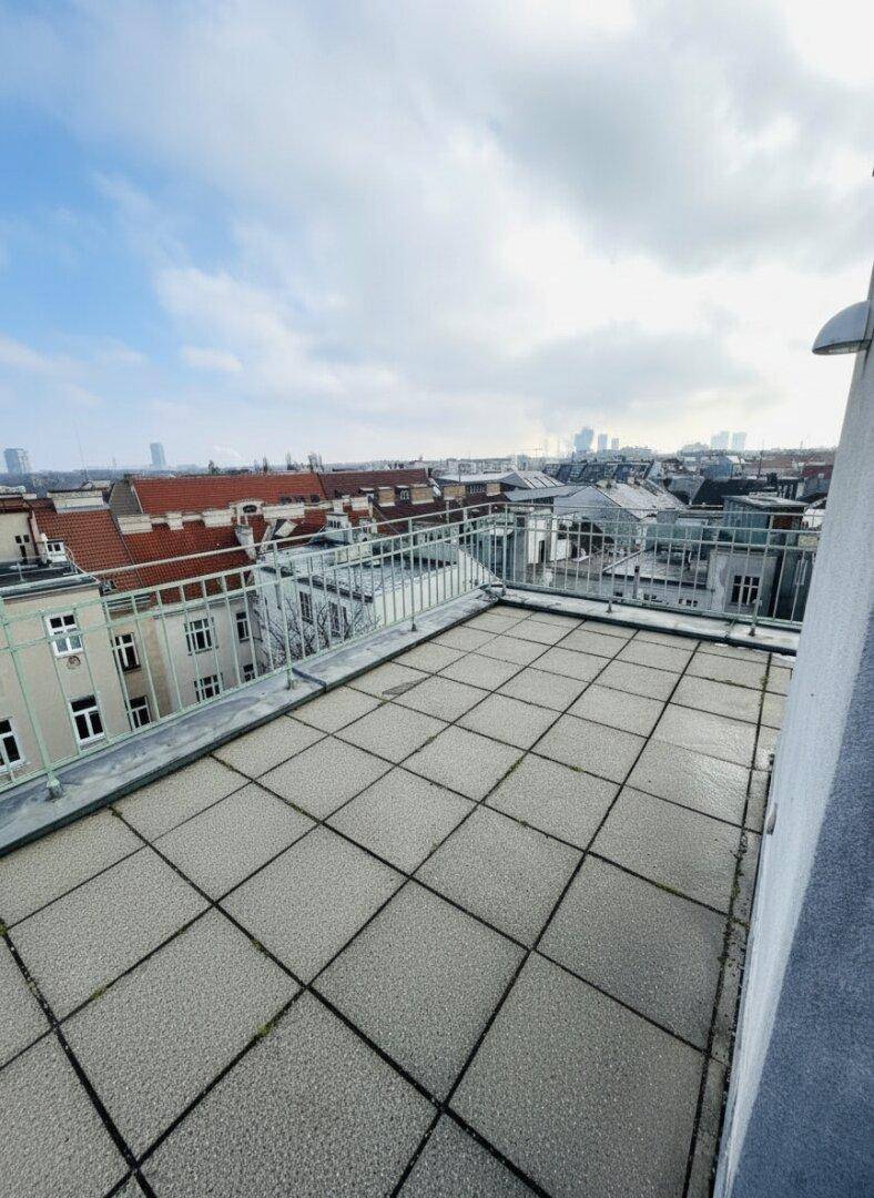 Geräumige Dachterrasse mit Fliesenboden und weitem Blick über die Stadt und die umliegenden Dächer.