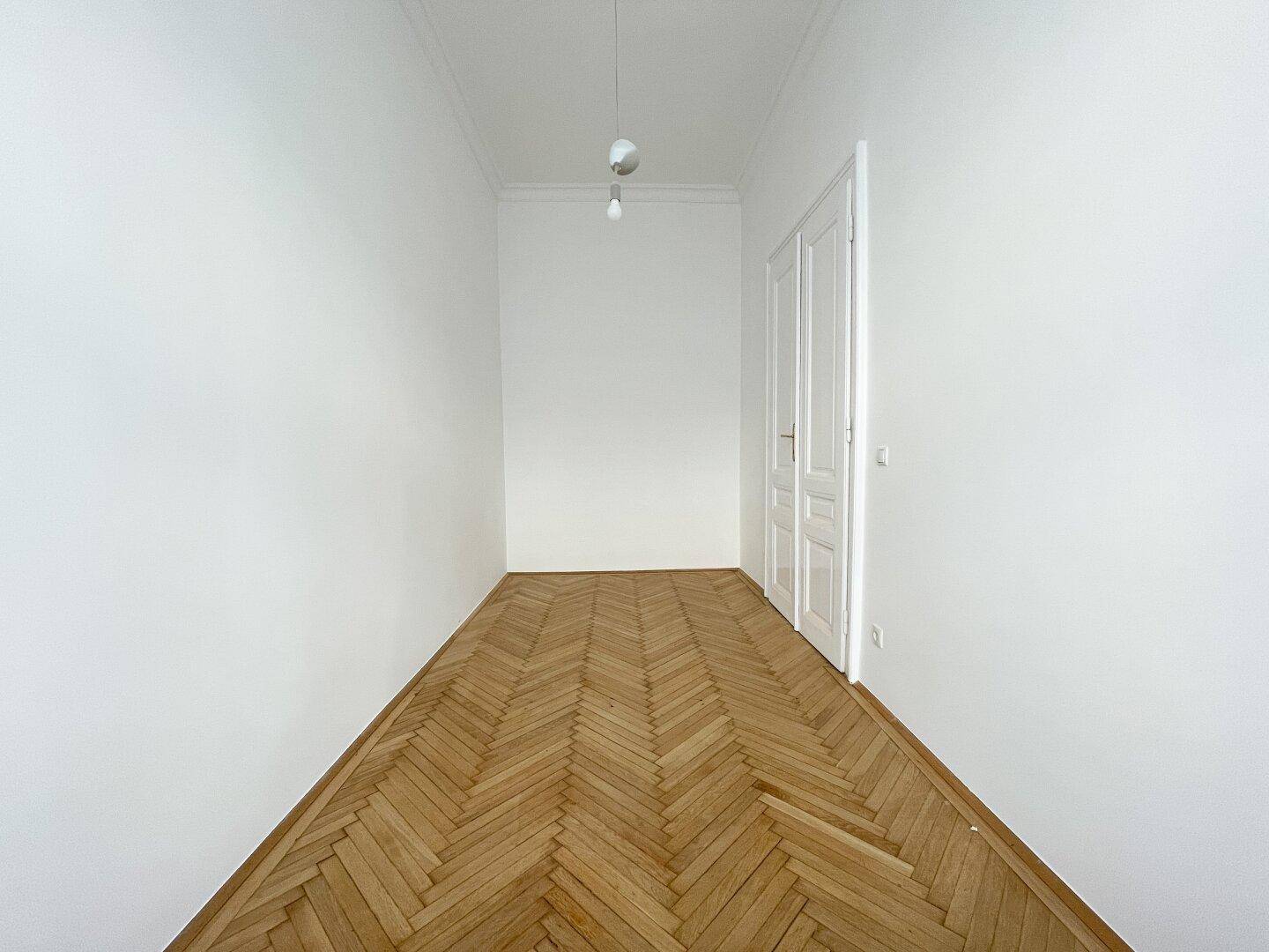 Leerer Raum mit Fischgrätparkett und hohen Decken, bereit für die individuelle Gestaltung.