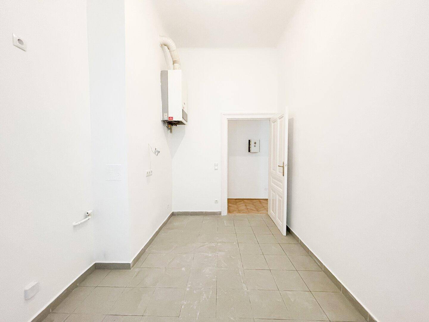 Raum mit Fliesenboden, Gastherme und Anschlüssen, ideal als Hauswirtschaftsraum oder Küche.