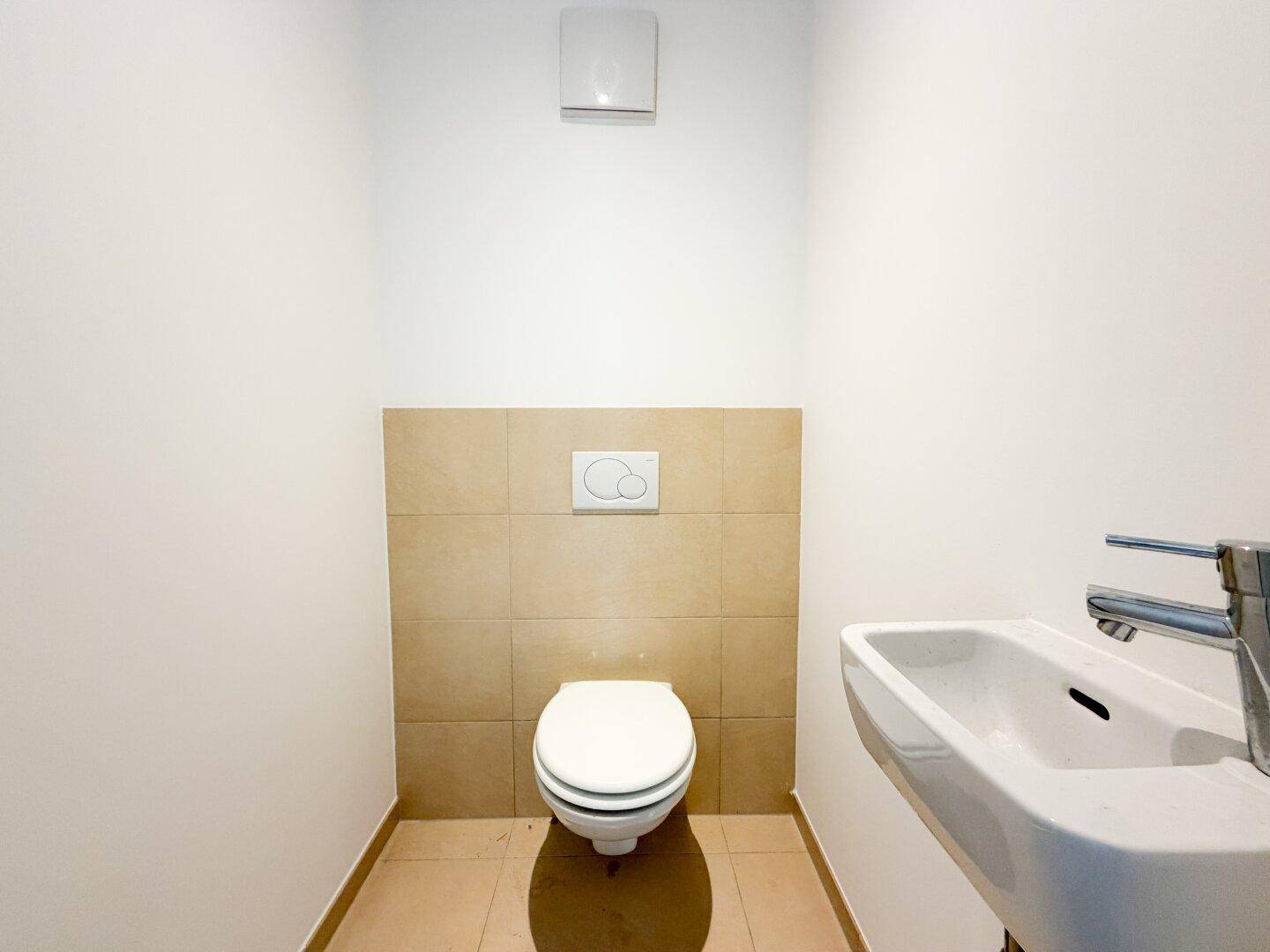 Modernes Gäste-WC mit Wand-WC, kleinem Waschbecken und Fliesenboden.